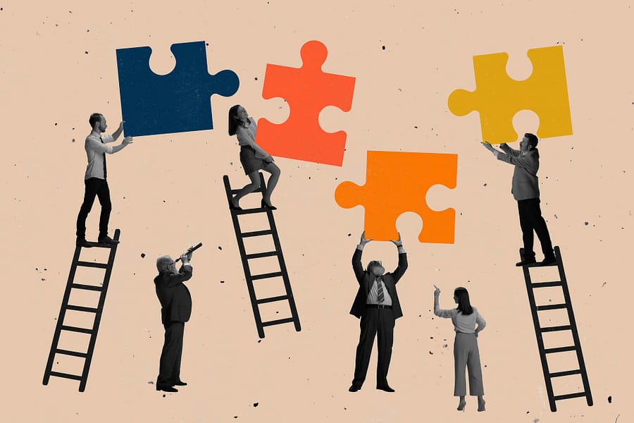 personnes juchées sur des échelles pour assembler des pièces de puzzle géantes